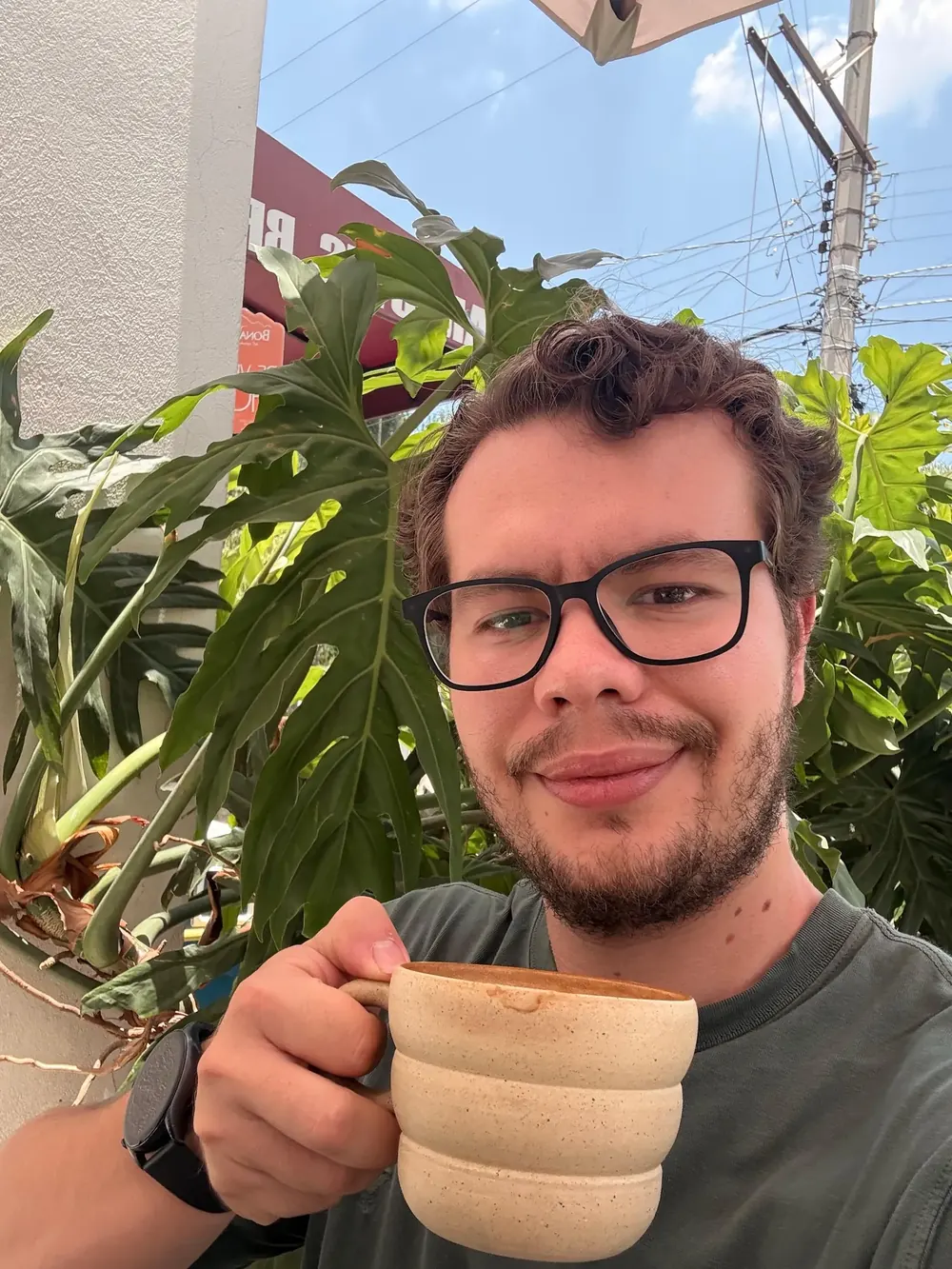 Eduardo Portillo sonriendo con una taza de café entre plantas